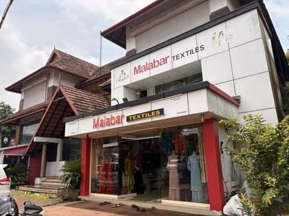 Street-facing frontage of nalukettu with shop units and Kerala roof detail